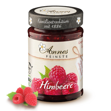 Annes Feinste Bio Himbeer-Konfitüre extra Glas Annes Feinste Bio Himbeer-Konfitüre extra, daneben Himbeeren.