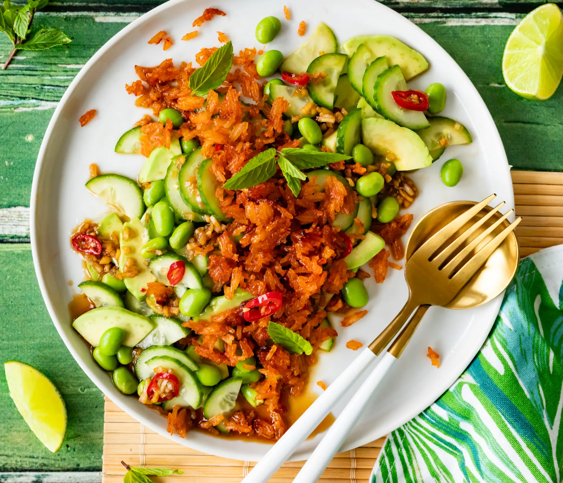 Crispy Reis Salat mit Gurke & Avocado Crispy Reis Salat mit Gurke, Avocado, Edamame und Minze auf einem weißen Teller, garniert mit Chilischoten.