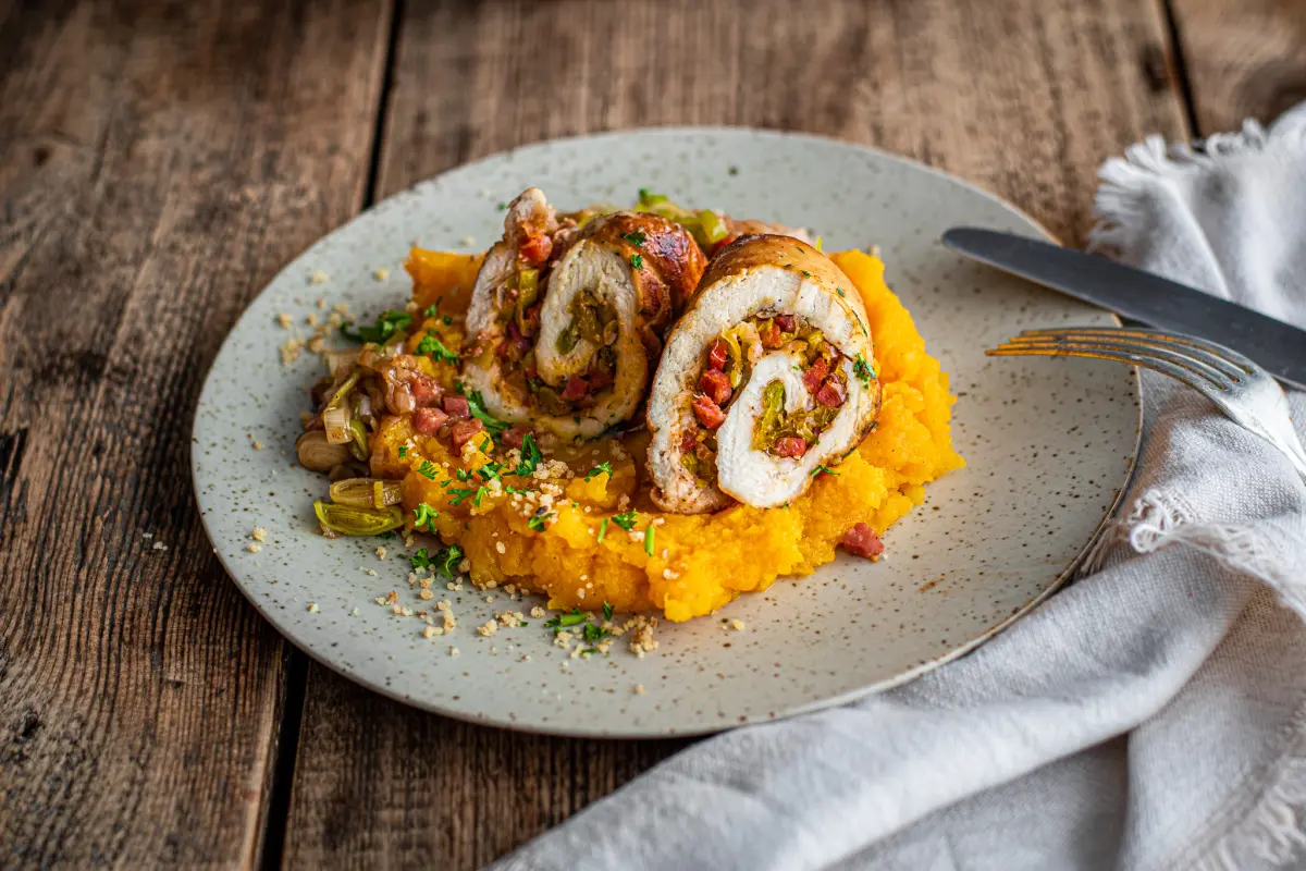 Gefüllte Hähnchenröllchen mit Kürbis-Kartoffelbrei Gefüllte Hähnchenröllchen mit Kürbis-Kartoffelbrei auf Teller serviert.