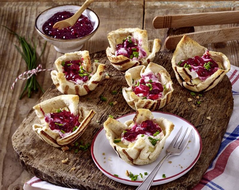 Rezeptbild gegrillte Toastkoerbchen, gefuellt mit Camenbert und Preiselbeeren. Im Hintergrund steht ein Schaelchen mit Preiselbeeren.
