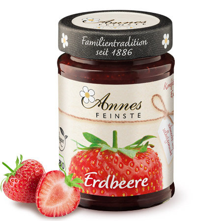 Annes Feinste Bio Erdbeer-Konfitüre extra Glas Annes Feinste Bio Erdbeer-Konfitüre extra, daneben Erdbeeren.
