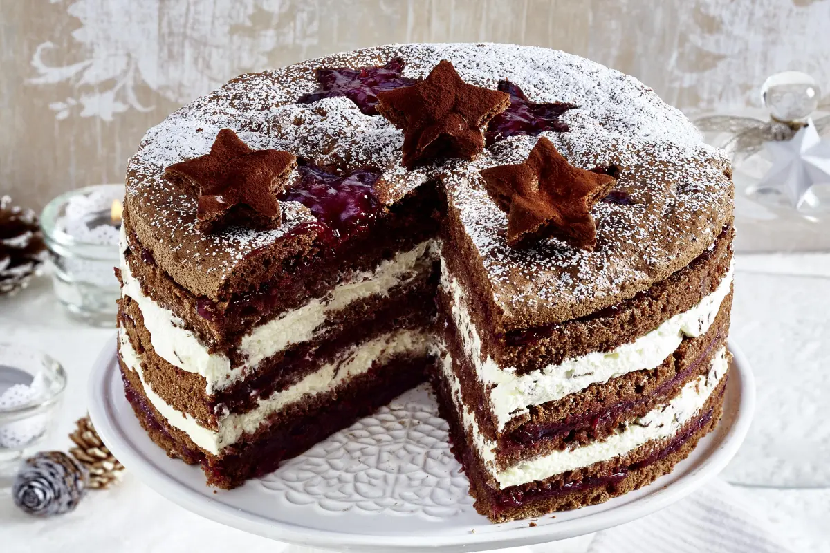 Weihnachtliche Schokotorte mit Preiselbeeren Schokotorte mit Preiselbeeren mit Anschnitt auf Tortenplatte.