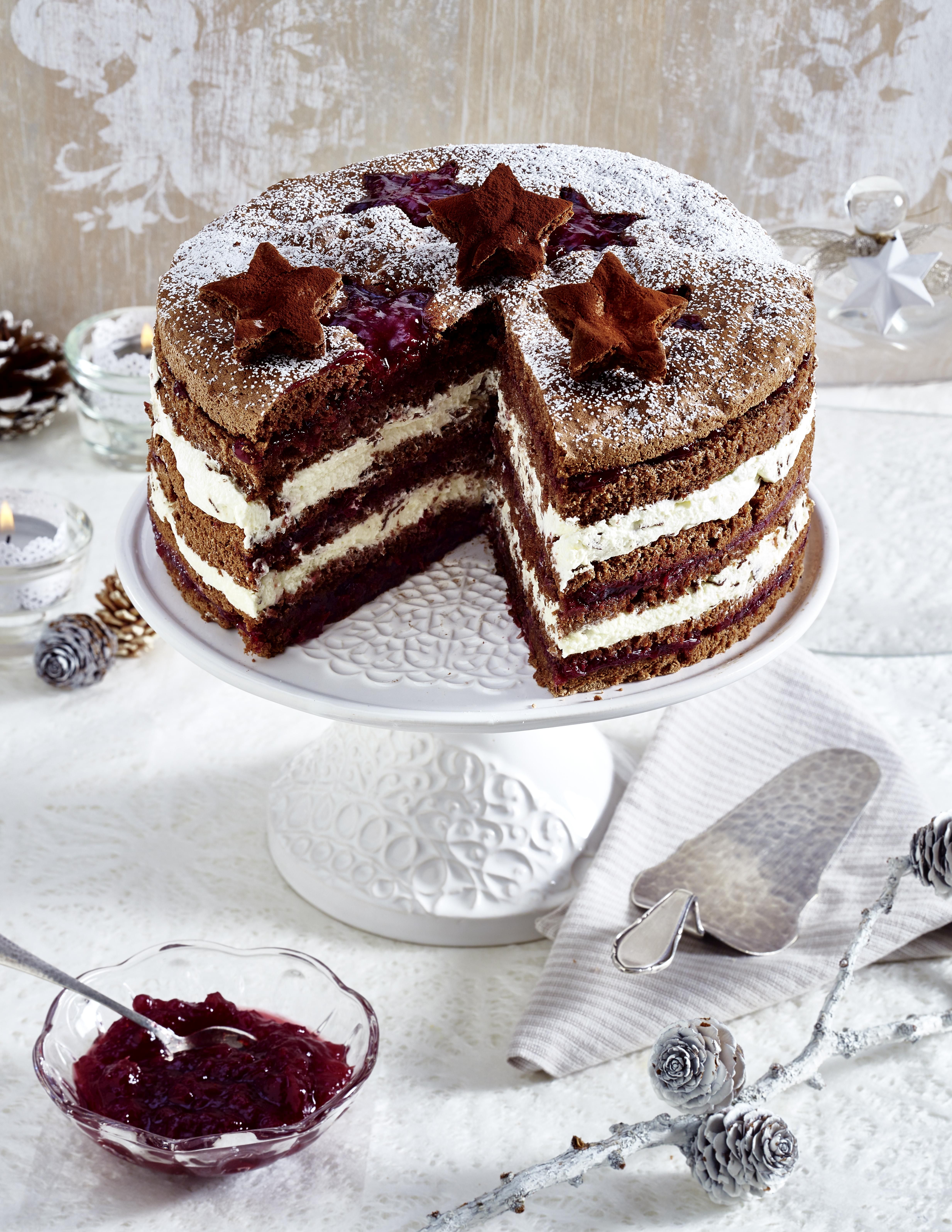 Wild-Preiselbeeren Auslese Angeschnittene Schokotorte mit Preiselbeeren auf Tortenpaltte und weihnachtlich dekoriertem Tisch.