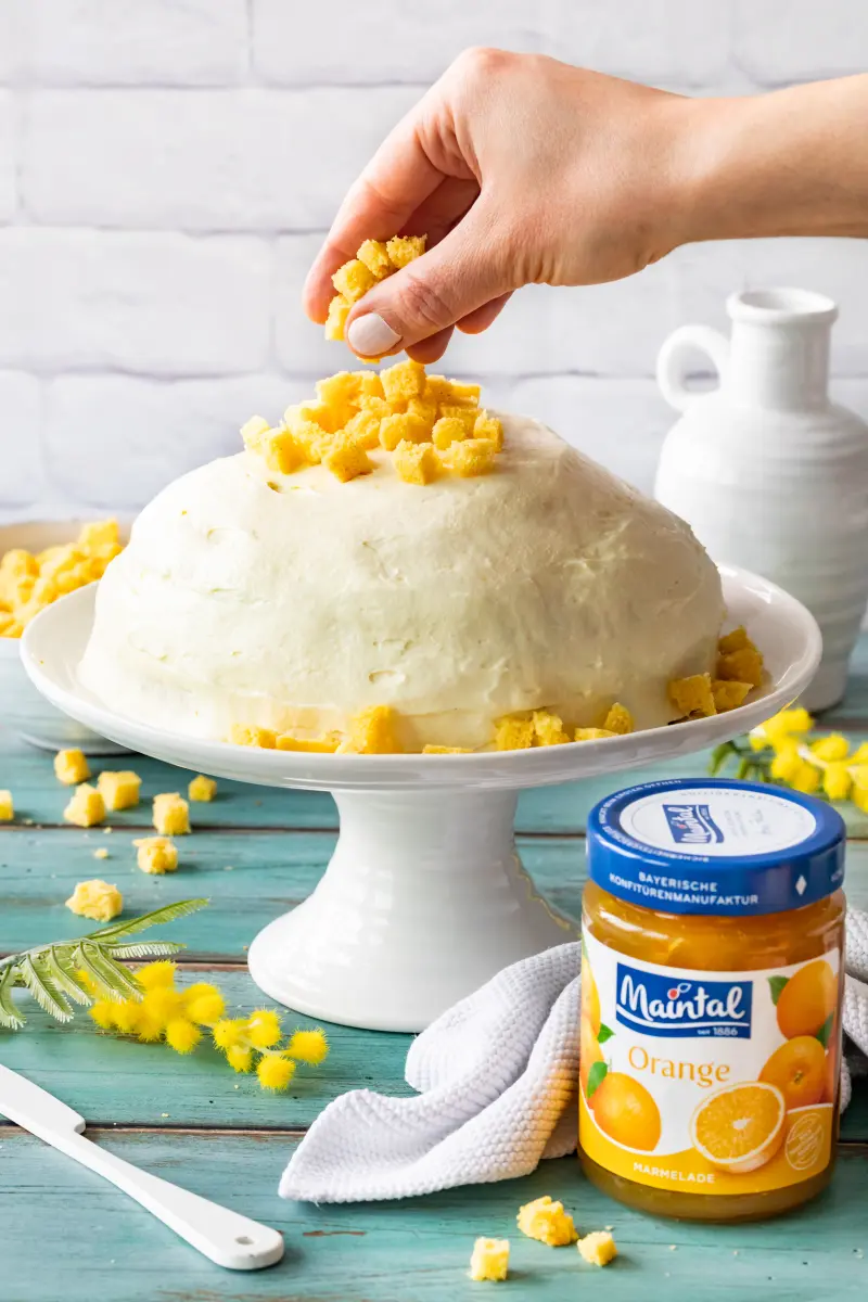 Torta Mimosa mit Zitronencreme und Orangen-Marmelade Die mit Creme eingestrichene Kuppeltorte wird mit Biskuitbröseln belegt.