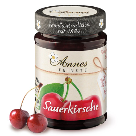 Annes Feinste Bio Sauerkirsch-Konfitüre extra Glas Annes Feinste Bio Sauerkirsch-Konfitüre extra, daneben zwei Kirschen.