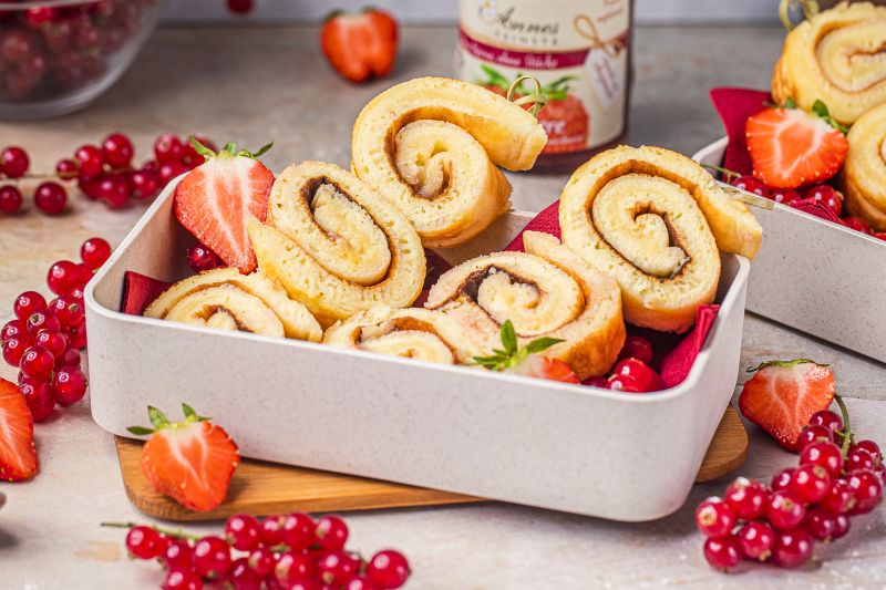 Pfannkuchenspieße Pfannkuchenspieße in Brotzeitboxen, darum herum rote Johannisbeeren und Erdbeeren.