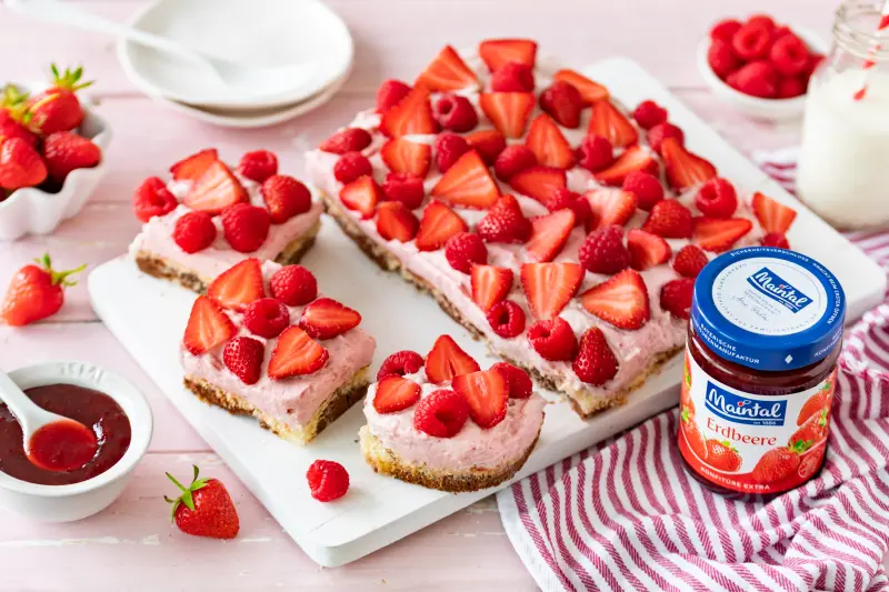 Blechkuchen mit Erdbeercreme und marmoriertem Boden Marmorierter Erdbeerkuchen mit Sahnecreme, frischen Erdbeeren und Himbeeren auf einer weißen Platte angerichtet