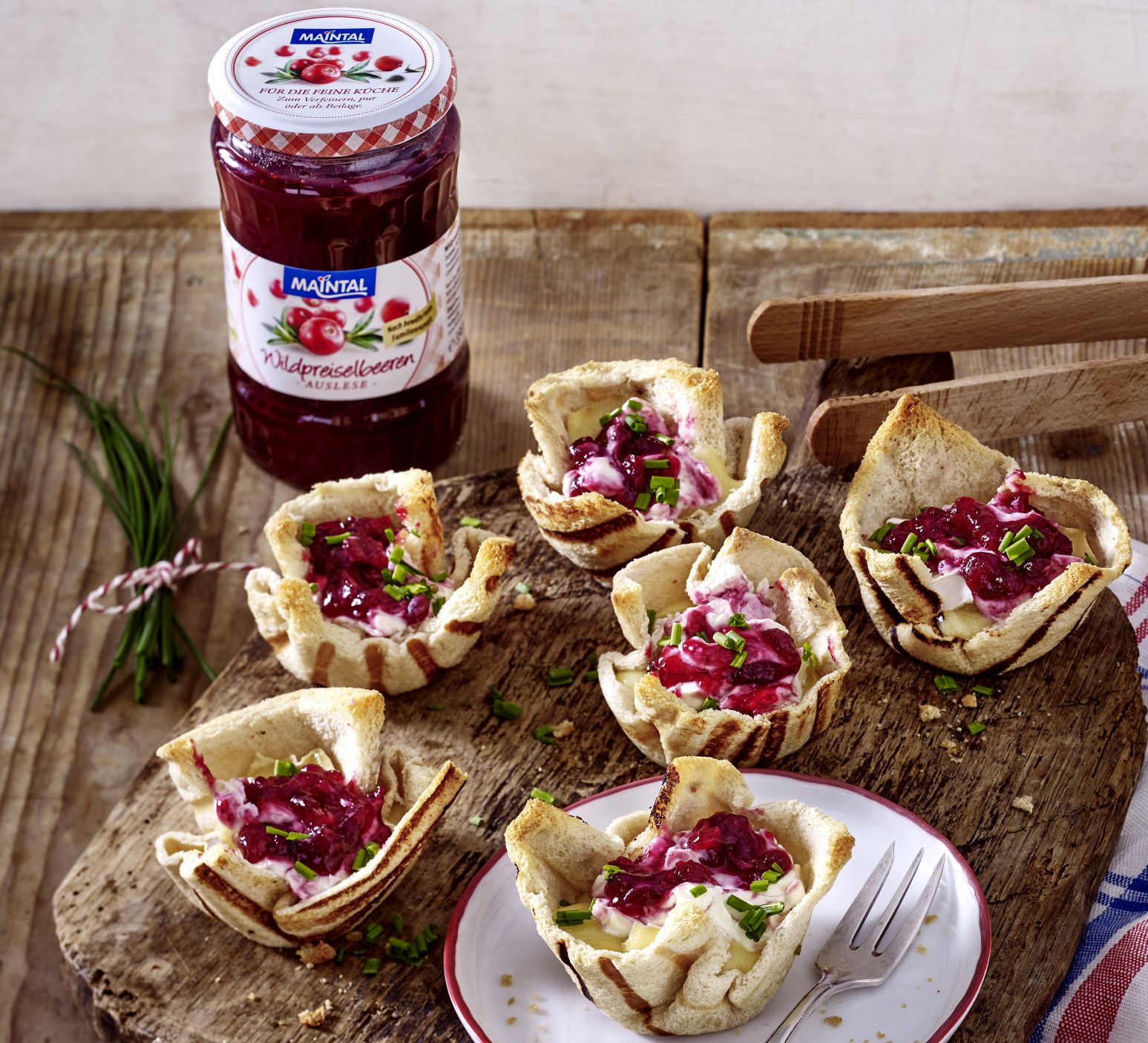 Toastgrillkörbchen mit Camembert und Wildpreiselbeeren Rezeptbild Toastgrillkoerbchen, gefuellt mit Camenbert und Preiselbeeren. Im Hintergrund steht ein Glas Maintal Preiselbeeren-Auslese.
