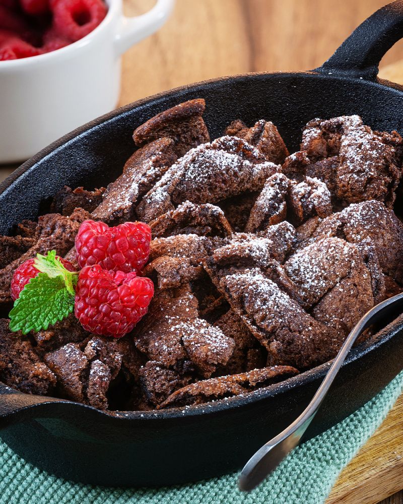 Schokoladen-Kaiserschmarrn mit Himbeerkompott Schokoladen-Kaiserschmarrn miit Himbeeren in Gusseisenpfanne.