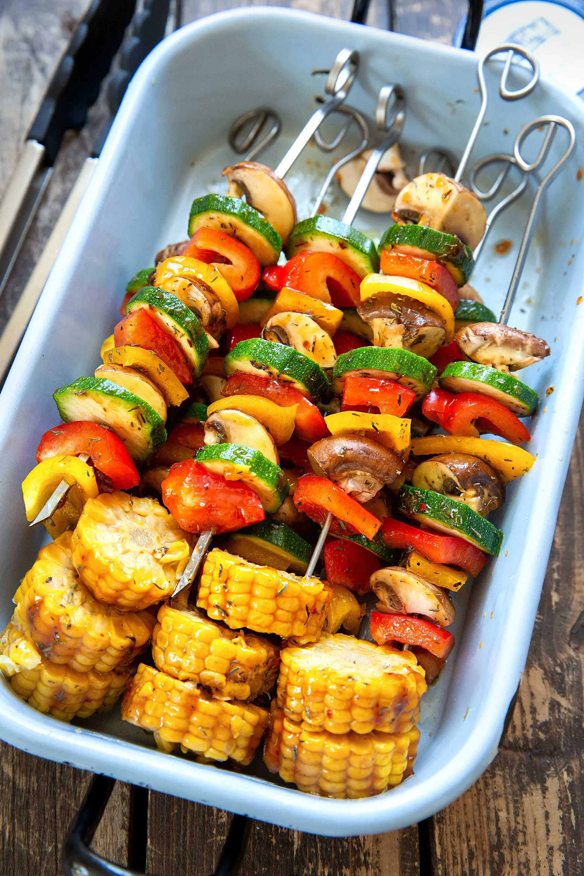 Sweet & Spicy Grill-Gemüsespieße mit Hagebuttennote Marinierte Gemüsespieße mit Paprika, Zucchini, Champignons und Mais in einer Schale vor dem Grillen