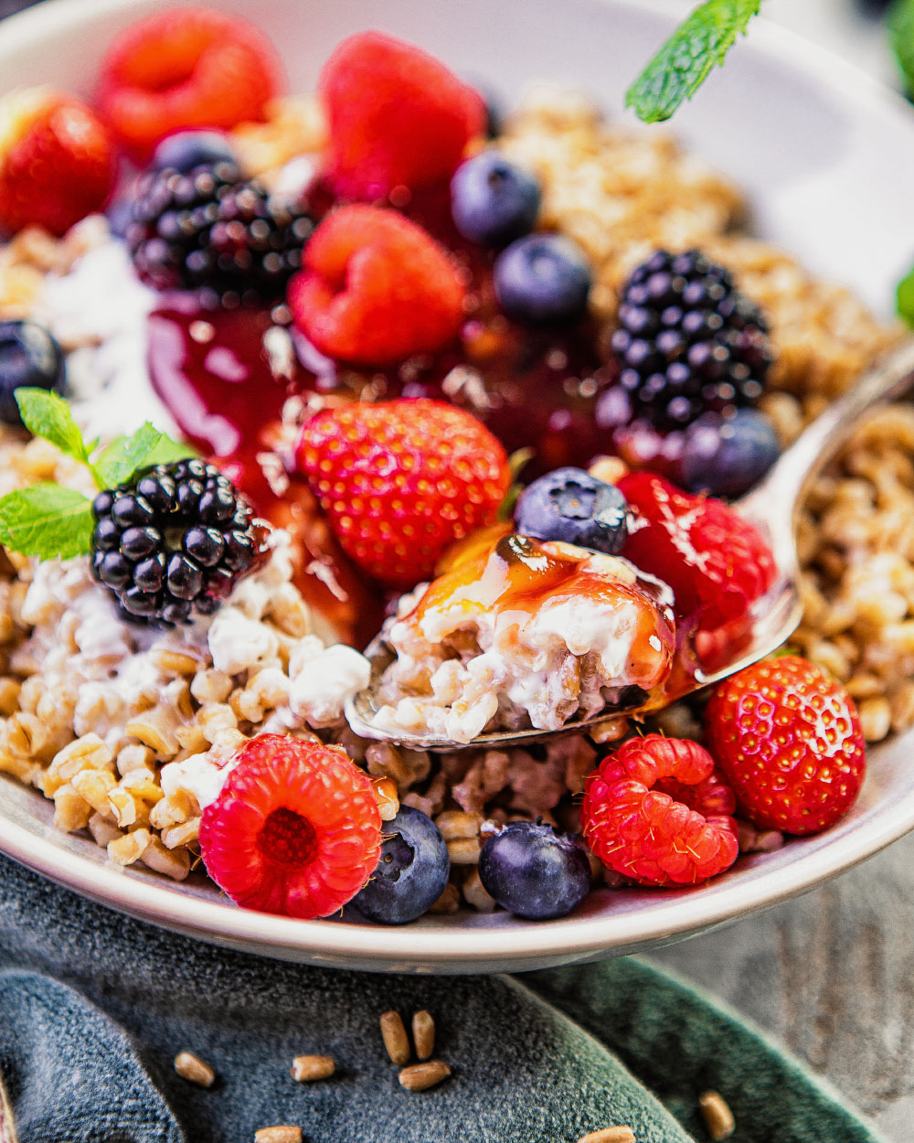 Frühstücksbowl mit Dinkel und Bio Gartenfrüchten Nahaufnahme Frühstücksbowl mit Dinkel und Bio Gartenfrüchten in Suppenteller mit Löffel in Bowlschüssel. seln jeweils mit frischen Früchten.