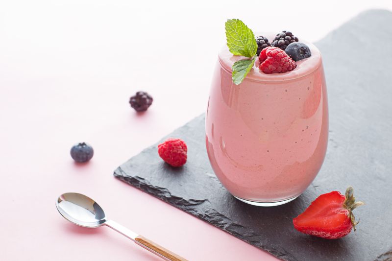 Vanilleeis-Shake mit Waldbeeren-Aufstrich Vanilleeis-Shake mit Waldbeeren-Aufstrich im Glas auf schwarzer Schieferplatte serviert.