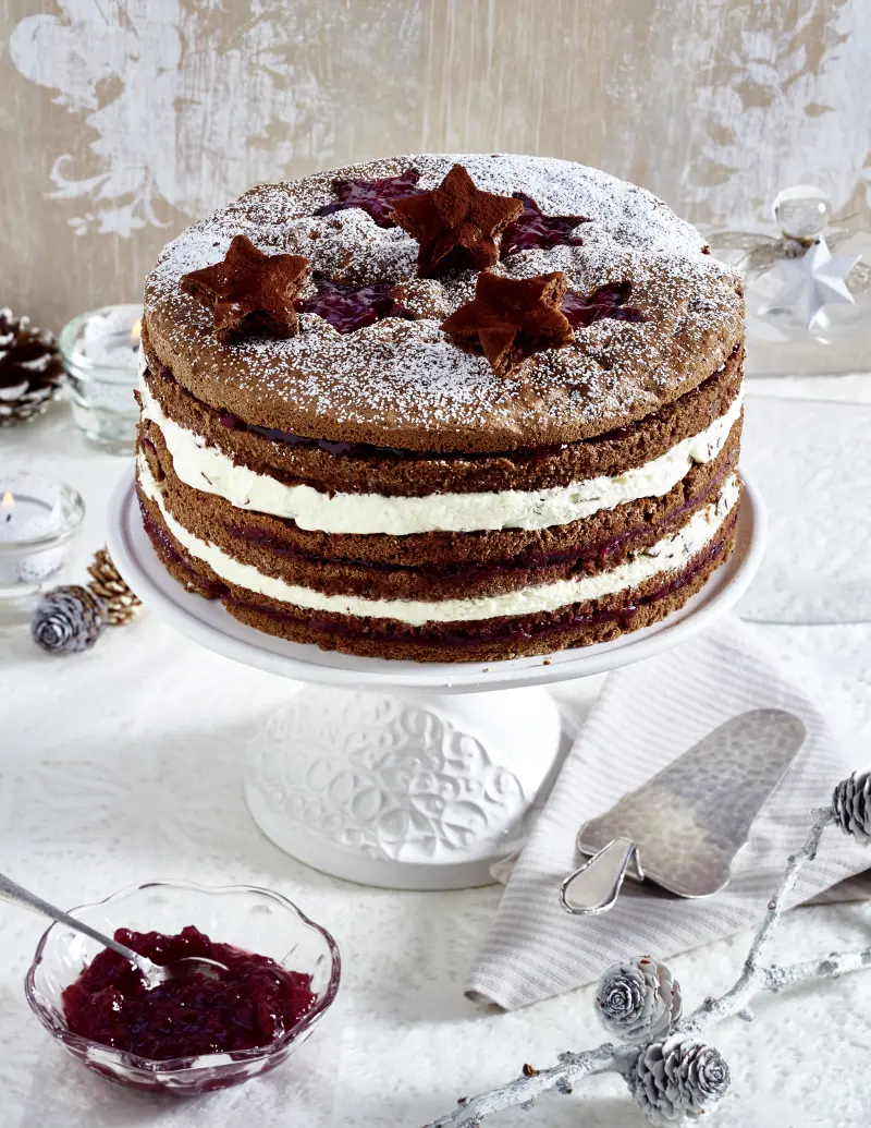 Serviervorschlag Weihnachtliche Schokotorte mit Preiselbeeren auf Tortenplatte, Schüssel mit Preiselbeeren, Tortenheber.