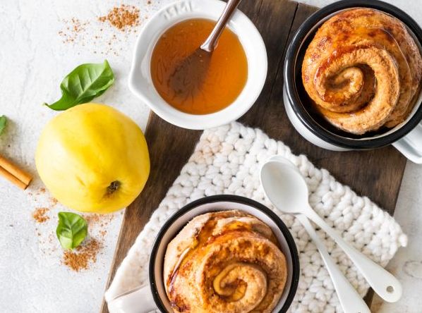 Zwei Tassenkuchen auf Brett mit zwei Löffeln, Quitte und ein Schüssel mit Quittengelee und Pinsel.