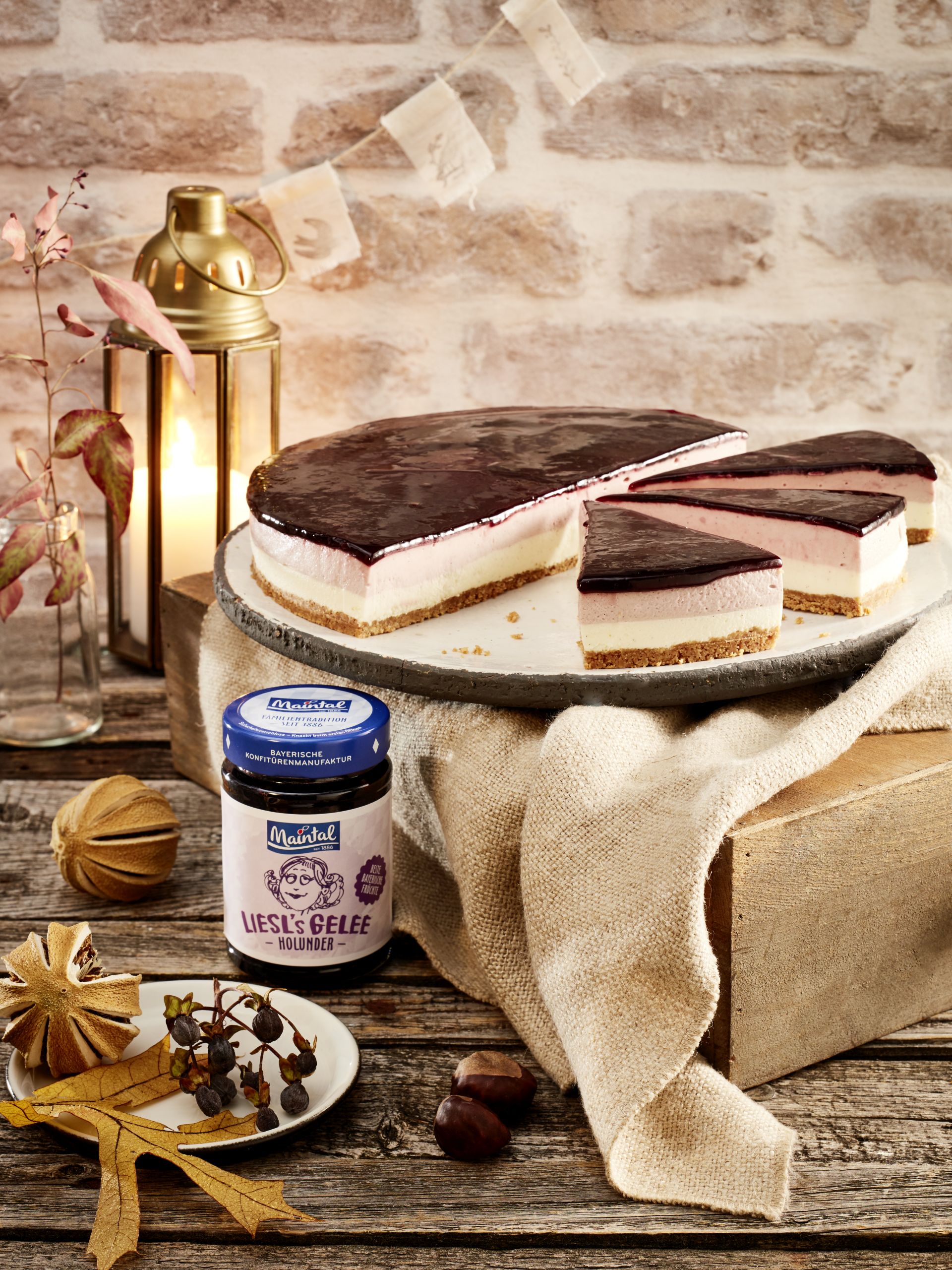 Panna-Cotta Torte mit Holunderspiegel I No bake Panna-cotta-Torte mit Keksboden, heller und Holunder-Cremeschicht sowie dunklem Holunderspiegel, daneben ein Glas Holunder-Gelee.