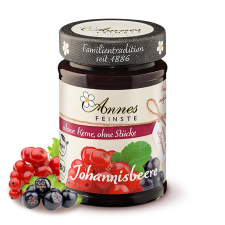 Annes Feinste Bio Johannisbeeren-Fruchtaufstrich fein passiert Glas Annes Feinste Bio Johannisbeeren-Fruchtaufstricn, daneben Johannisbeeren.